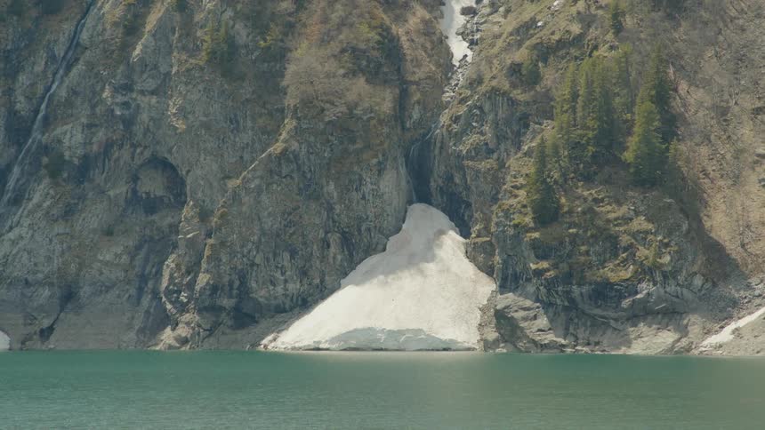 Sand piles up in a cove on the side of a cliff in the coast