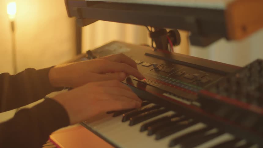 A man records music on two keyboards stacked together