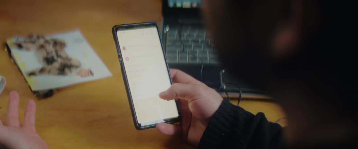 Boy sitting in front of a laptop stands up after reading a text on his phone