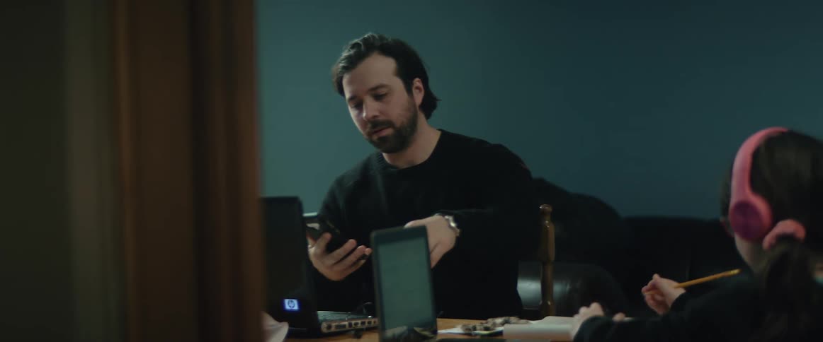 Father and daughter sitting at home using laptops and cellphones