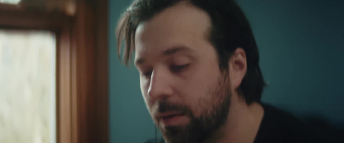 A man moves his head to music while typing on his laptop at home