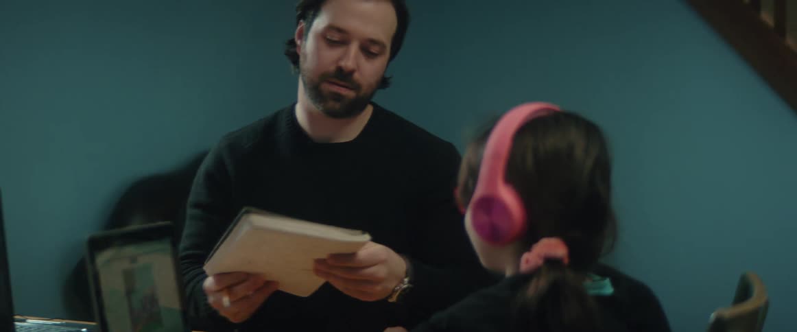 Father helps his daughter with homework in the living room
