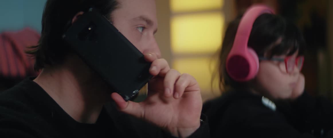 Father talking on a smartphone helps daughter with homework
