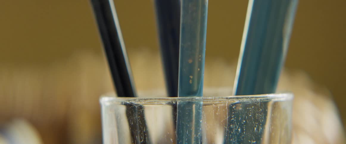 Painter changes brushes inside a glass stained with paint