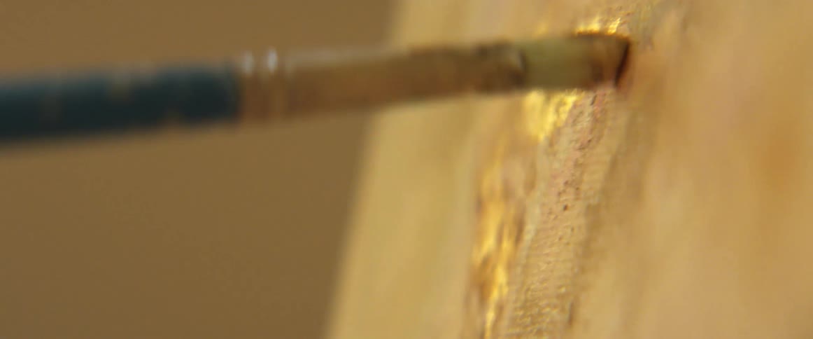 A paint brush applies paint to a canvas