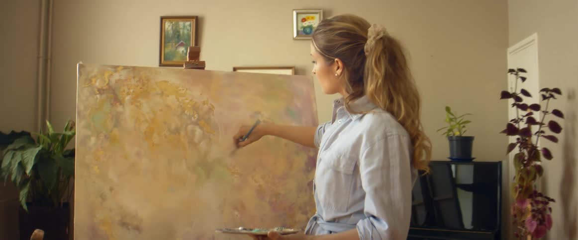 A woman is painting on a canvas indoors