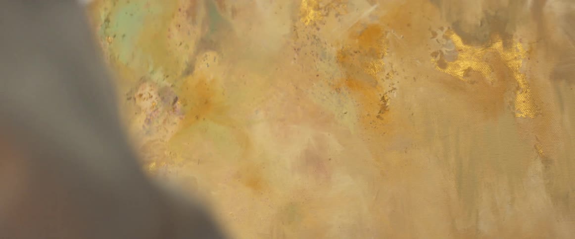 A male painter applies paint to a canvas using small and quick brushstrokes