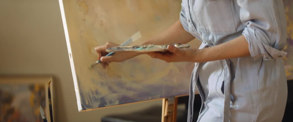 A woman is painting on a canvas