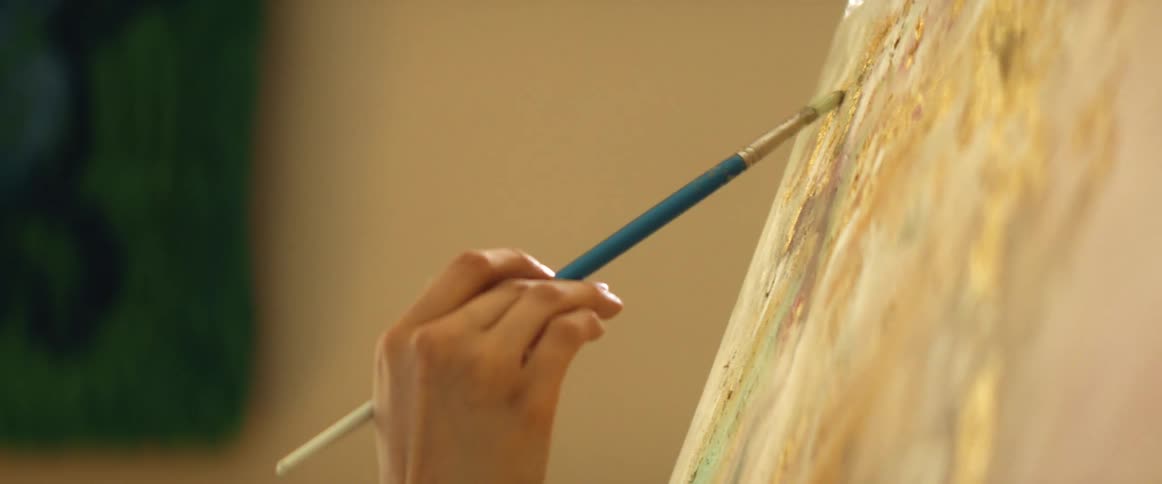 Close up of a female hand painting on a canvas