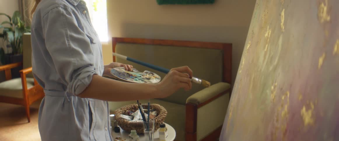 A woman paints on a canvas in her home