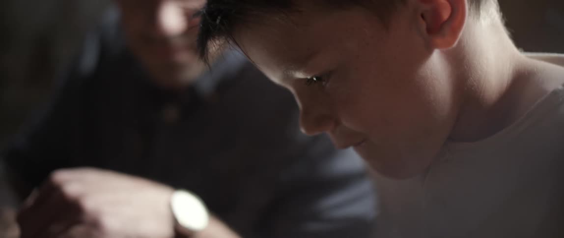 Young boy looking down and admiring something with a man observing him
