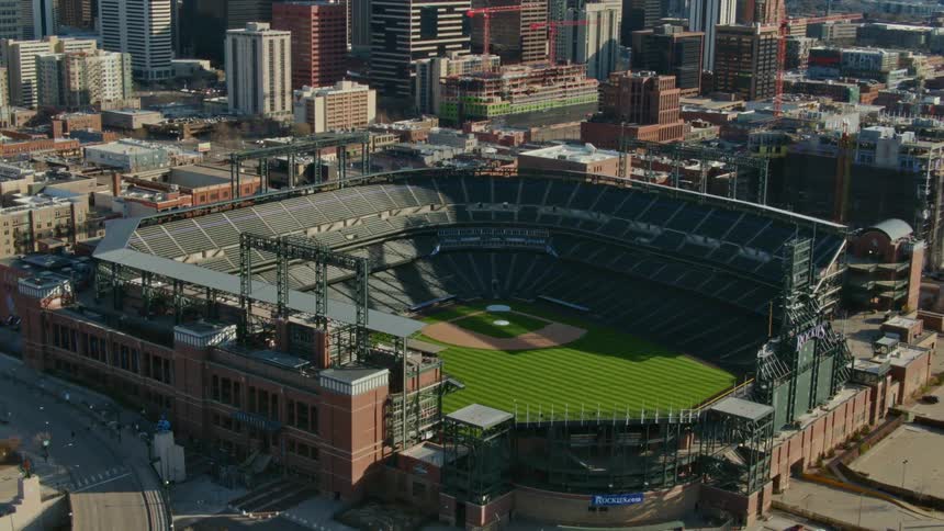 A baseball stadium is surrounded by skyscrapers in a city