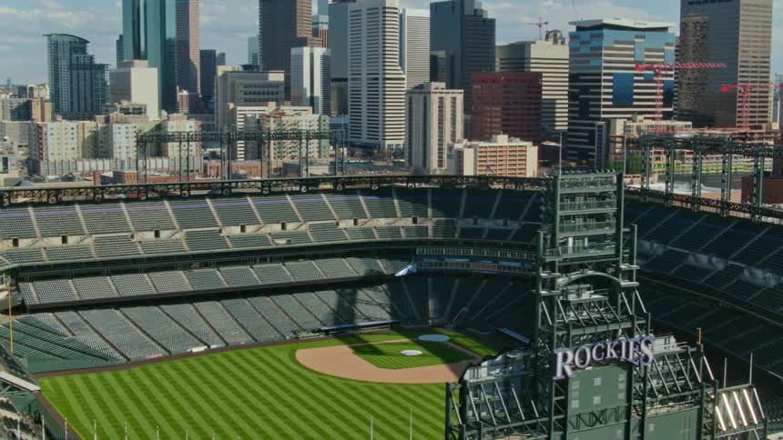 A baseball stadium with the city skyline buildings the sky and clouds in the background