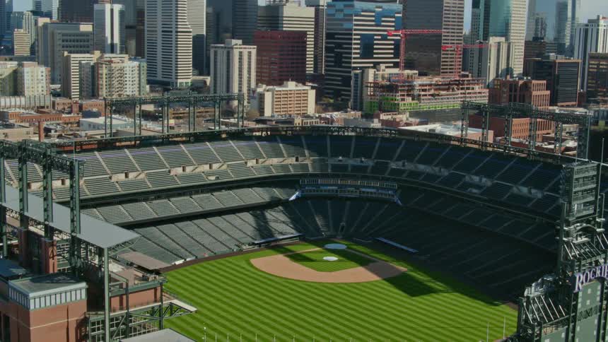 A baseball stadium with the city skyline buildings the sky and clouds in the background