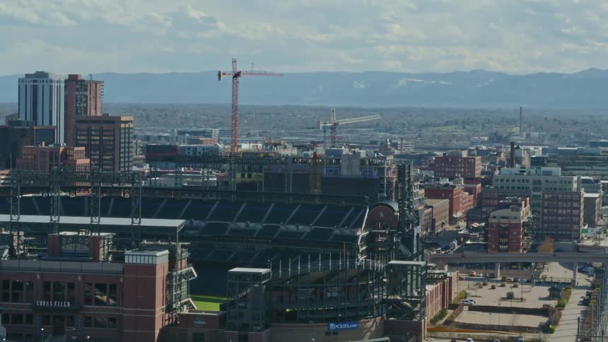 Construction cranes towering over a staidum in construction in the city