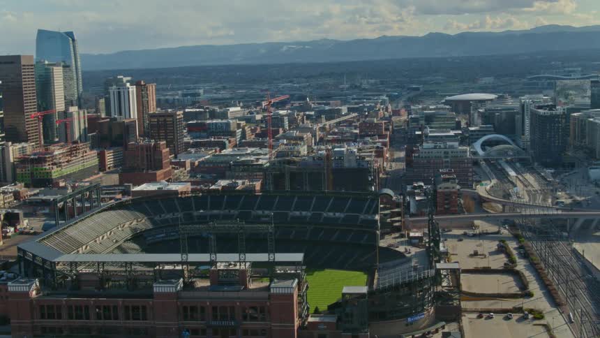 The green grass of a ball park stands out in a city skyline