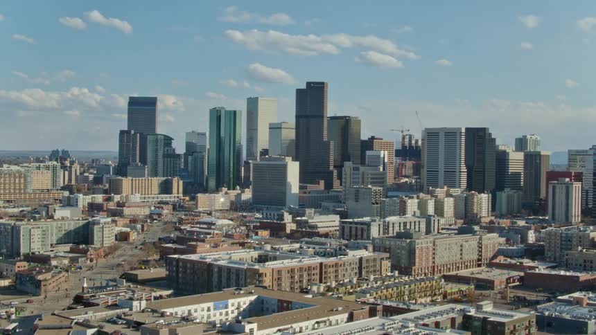 A city skyline with buildings roads and skyscrapers with the sky and clouds in the background