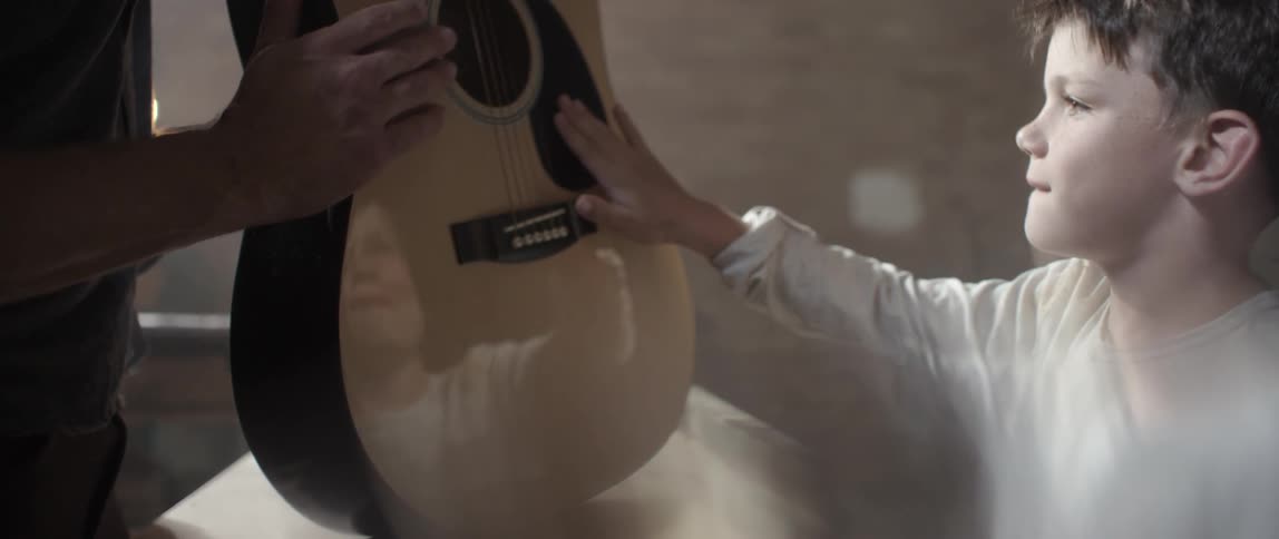 Young boy admiring a freshly made guitar