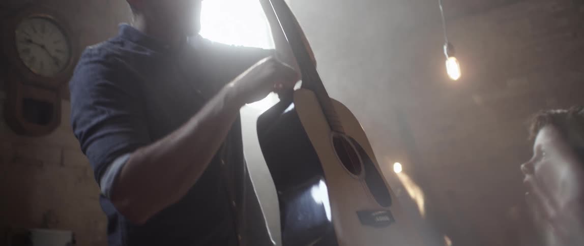 A man shows a boy a guitar
