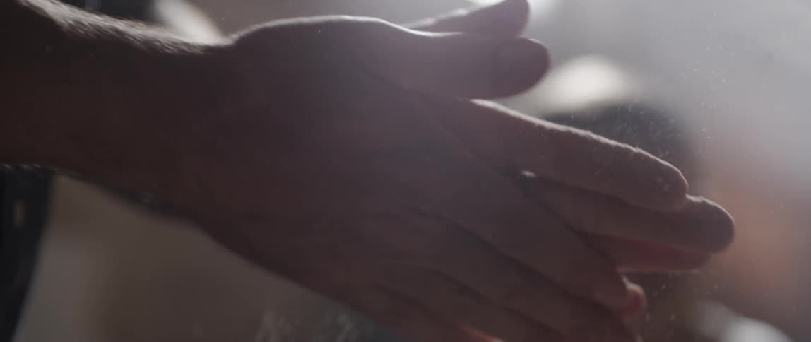 A man wipes his hands with dust for grip