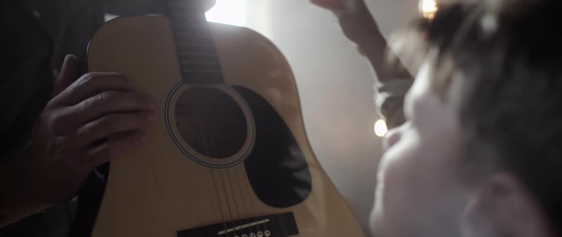 Young boy admiring a guitar that is being held by an older person