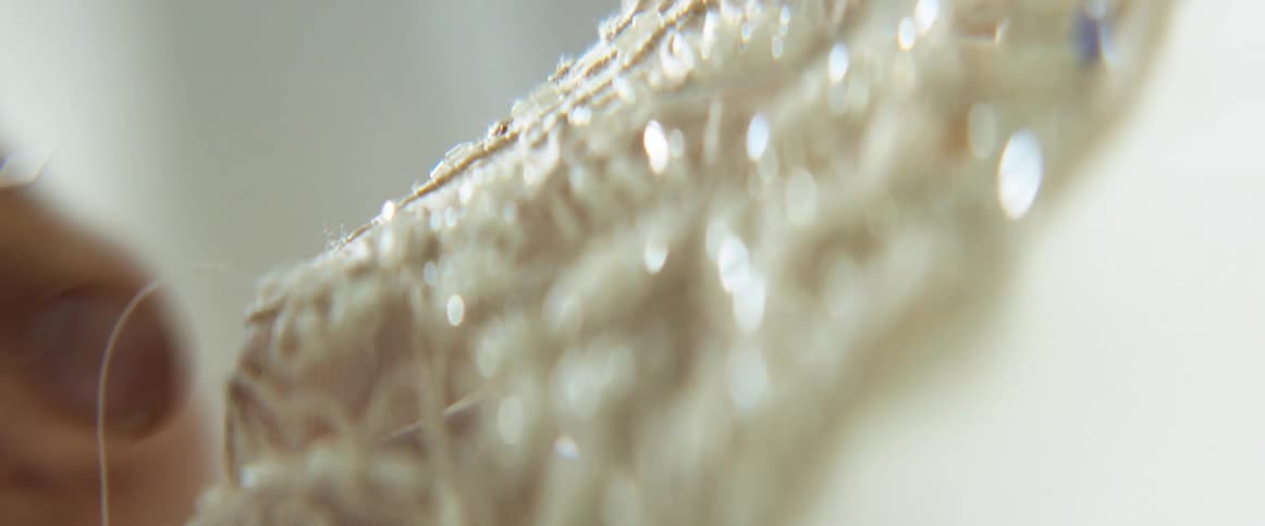 Close up of a needle sewing through an embroided cloth