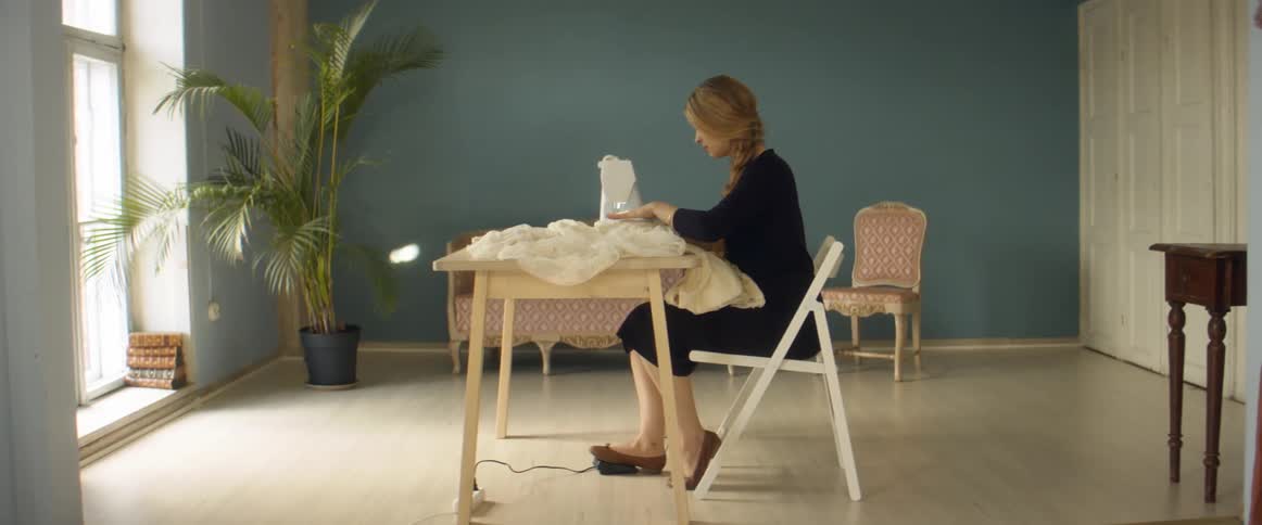 A woman is sitting at a table and sewing