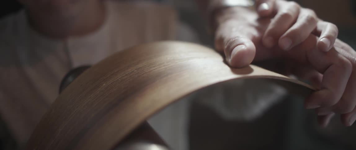 A thin bent piece of wood being sanded