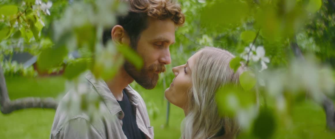 A couple exchanges a romantic kiss outdoors