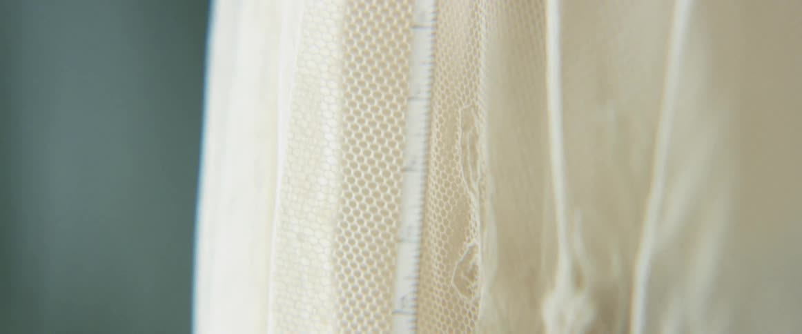 Close up of a measuring tape put against a laced cloth
