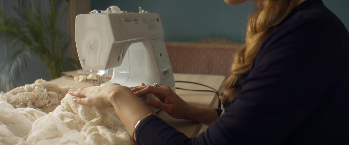 Woman making a dress in a sewing machine inside a room