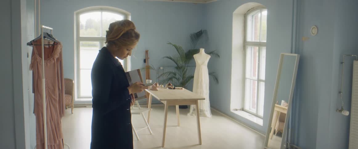 Female clothing designer stops inside studio to check her mobile phone