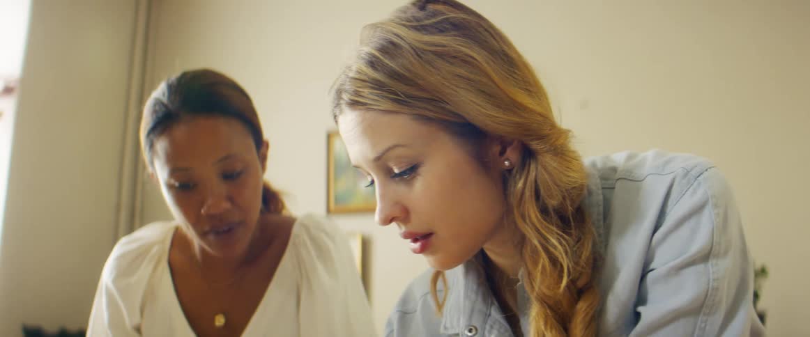 Two women stand in office holding discussion
