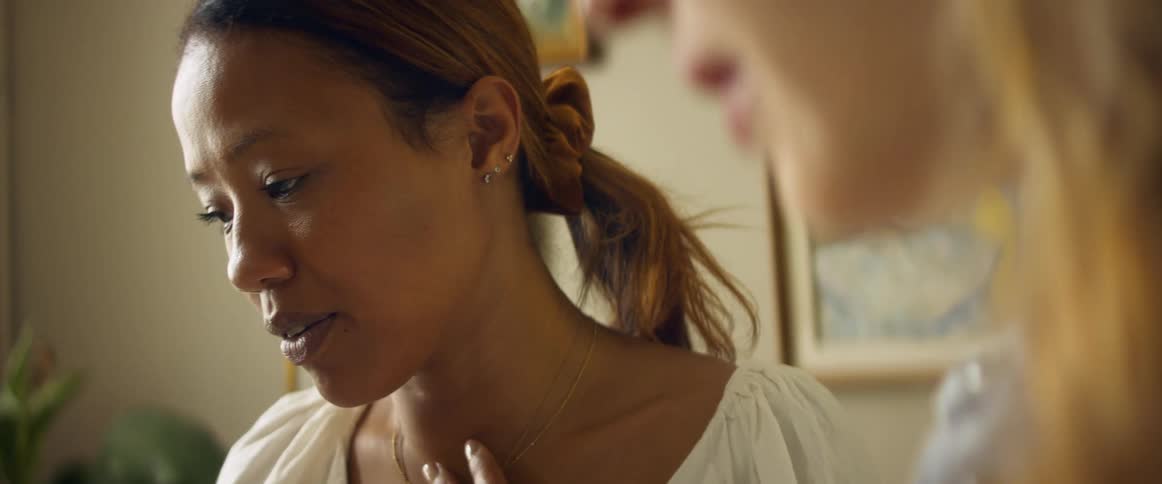 Two woman are talking as one of them looks down at an object