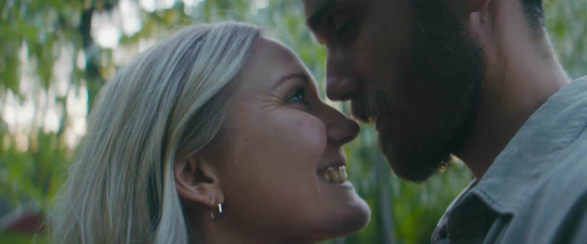 A man and woman put their noses together and laugh