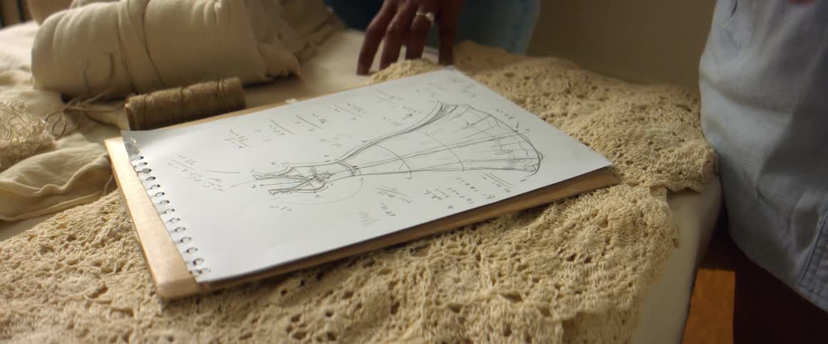 Two women in an office look at a sketch of a dress and discuss it