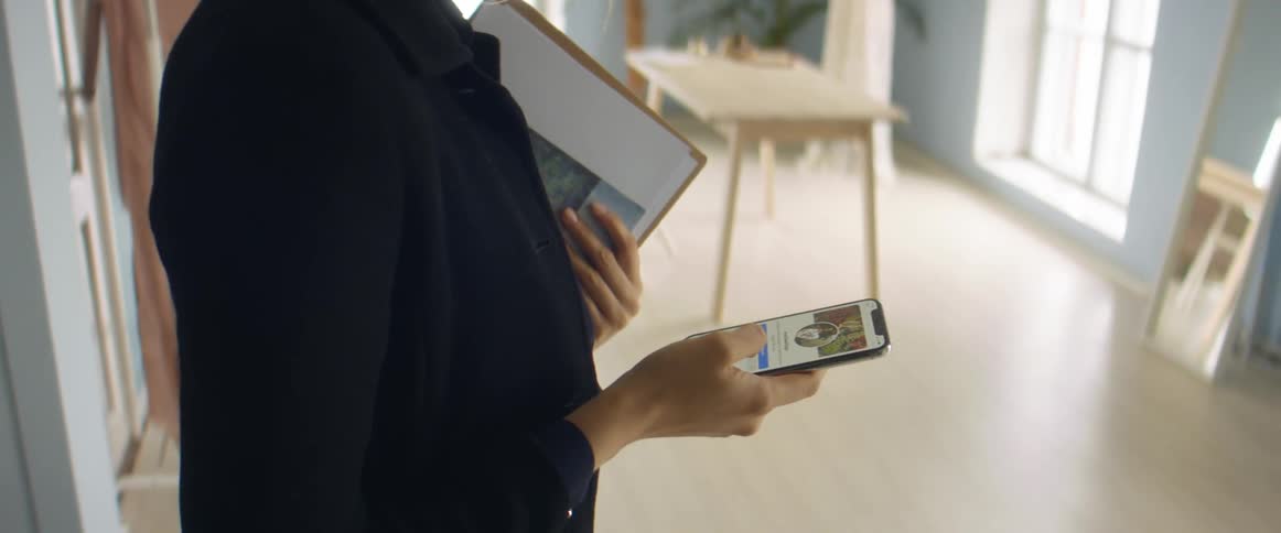 A woman is standing in a room and looking at a cellphone