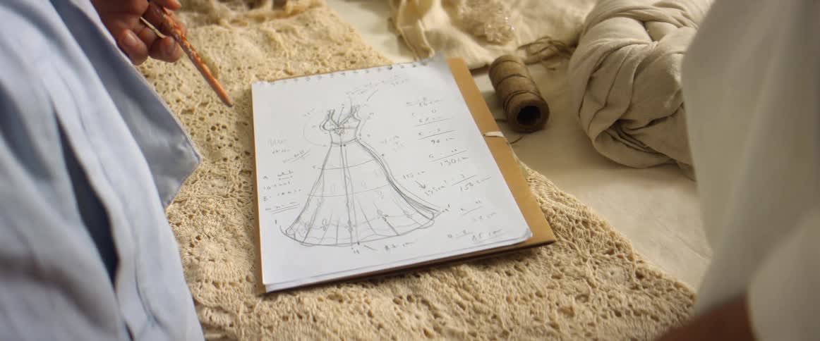 Coworkers discuss clothing design sitting on surface near fabric
