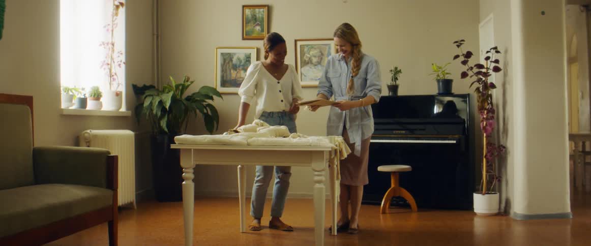 Two women stand beside each other at a table looking at a clipboard