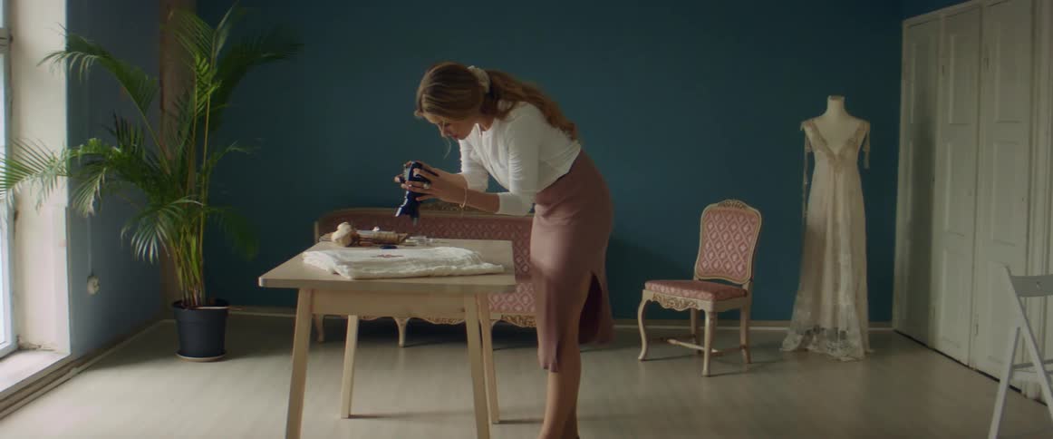 A woman takes picture of an object lying on a desk using dslr camera
