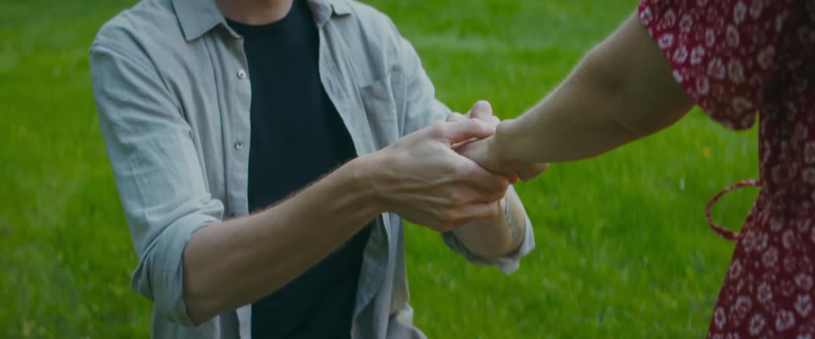 A man puts a ring on a woman on his knees and they embrace afterwards
