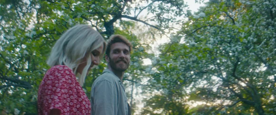 A man and woman walk towards a house and stop and kiss