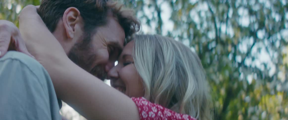 A woman laughs and hugs and kisses her boyfriend
