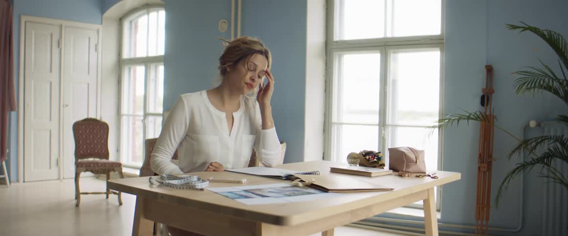 A woman sits down at the table looking at a pad