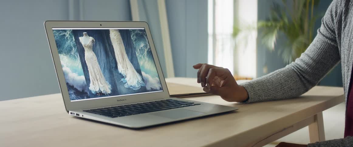 Person lightly strokes finger over dress pictured on laptop screen
