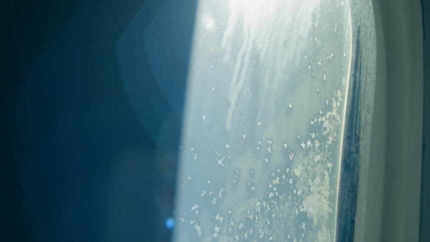 Close up of an airplane window as sunshine passes through
