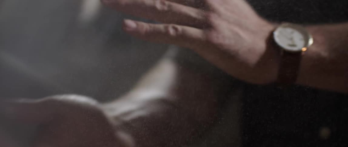 A man wipes his hands together, clearing them of sawdust