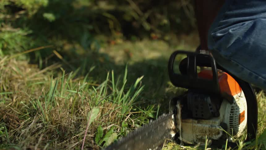 A person starts a saw outside