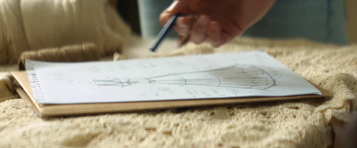 Fashion designer drawing the sketch of a dress on paper