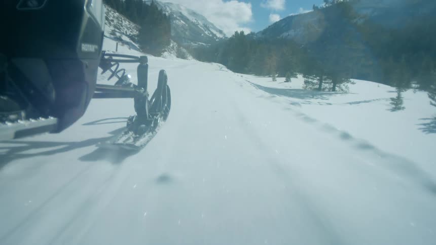 Snowmobile ski sliding over a snow covered road near the mountains at winter